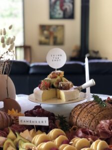 wheel of brie in burnt orange themed grazing table